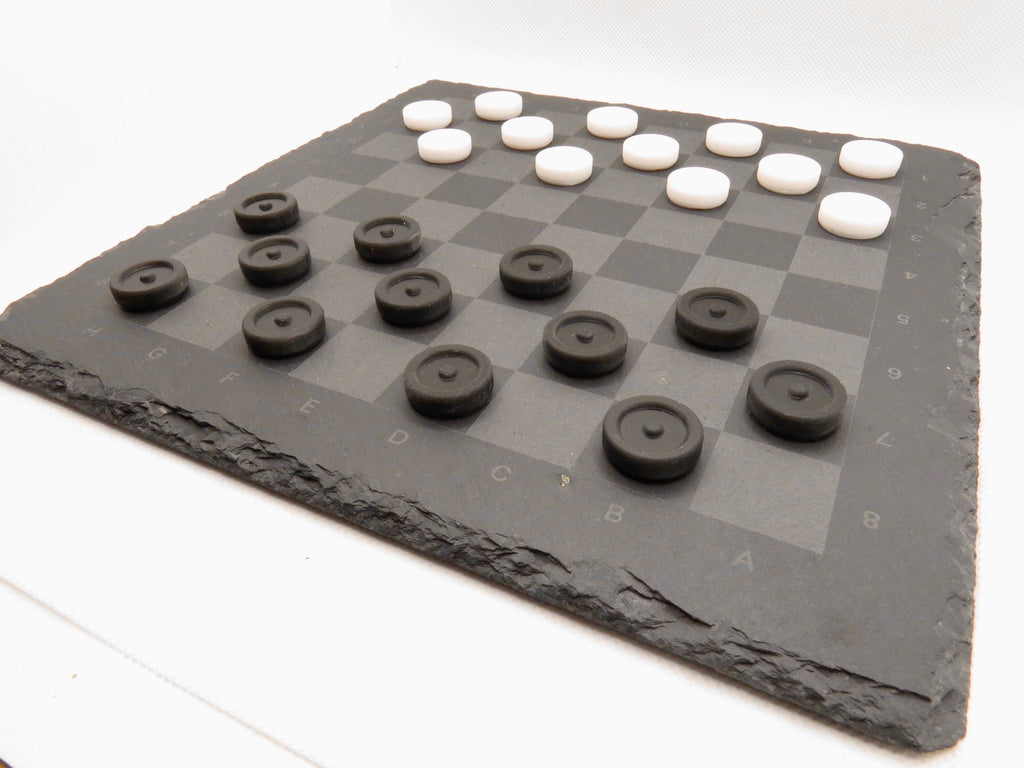 Aufgebautes Dame-Spiel seitlich: Modernes Design des Strategie-Klassikers auf grauer Steinplatte.