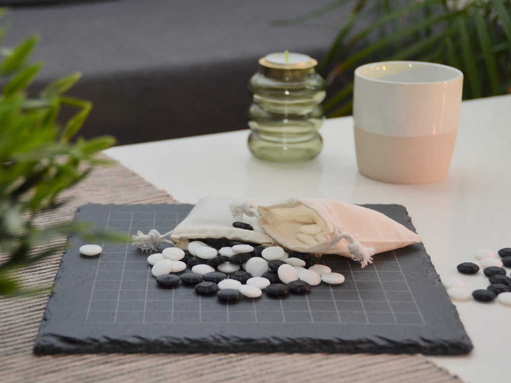 Edles Go-Brett im Wohnzimmer: Schieferplatte mit Spielsteinen dekorativ auf hellem Tisch platziert.