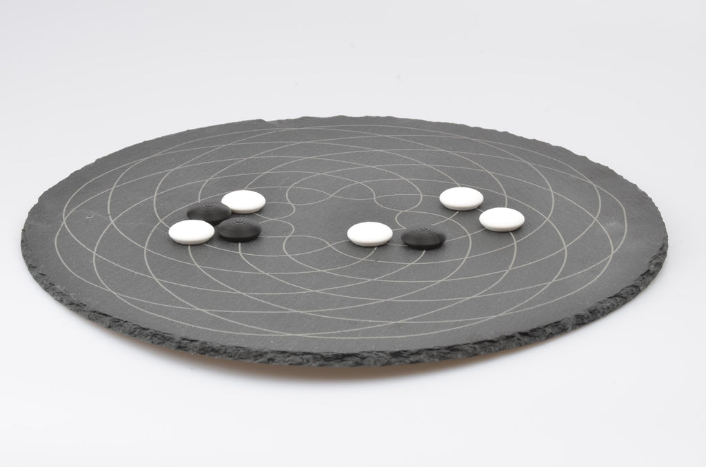 Go Strategie-Spiel Aufbau: Platzierte Spielsteine auf dem runden Design-Brett in Spielsituation.
