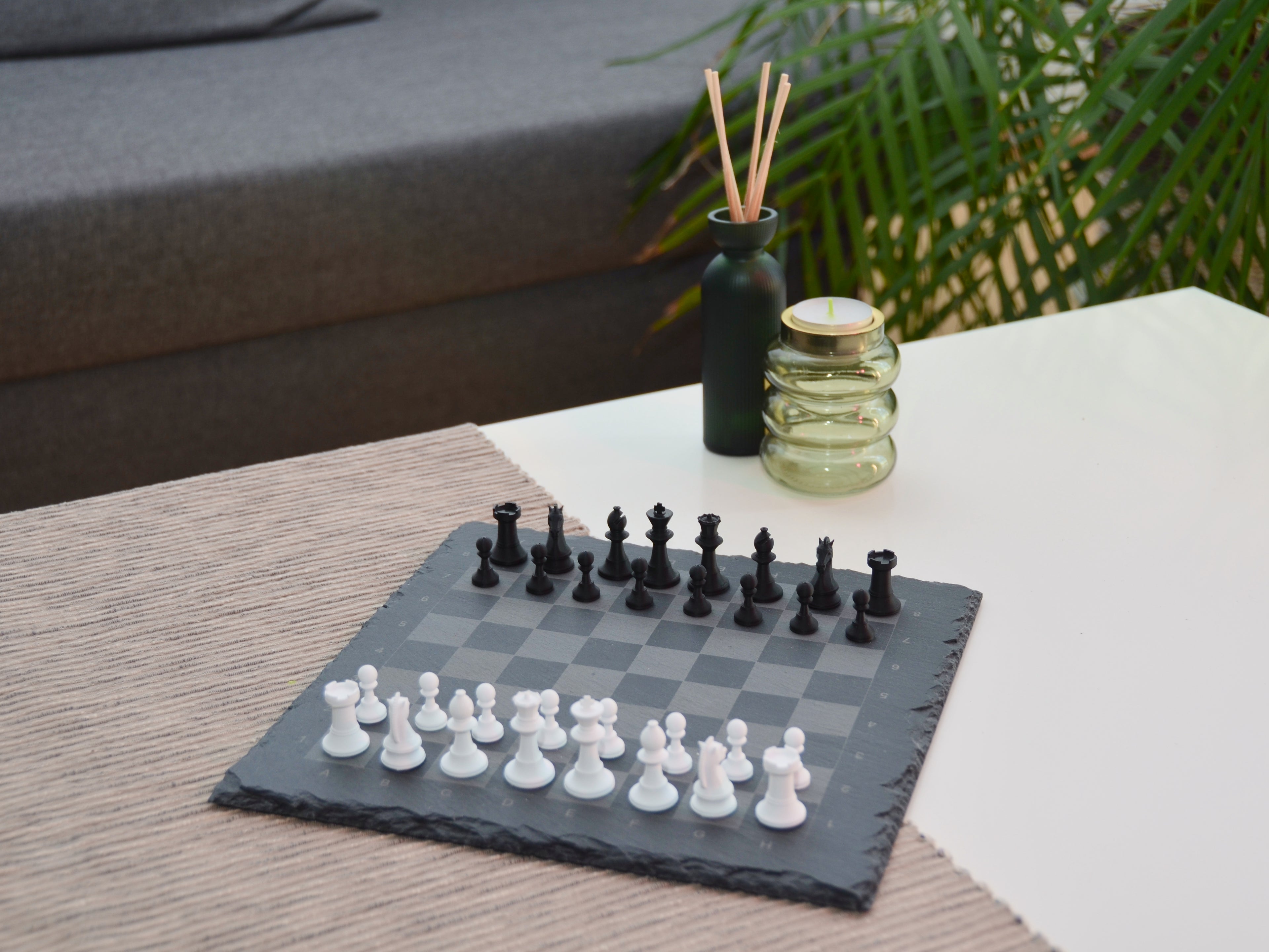 Modernes Schachbrett aus Schiefer als stilvolle Deko im Wohnzimmer auf hellem Tisch platziert.