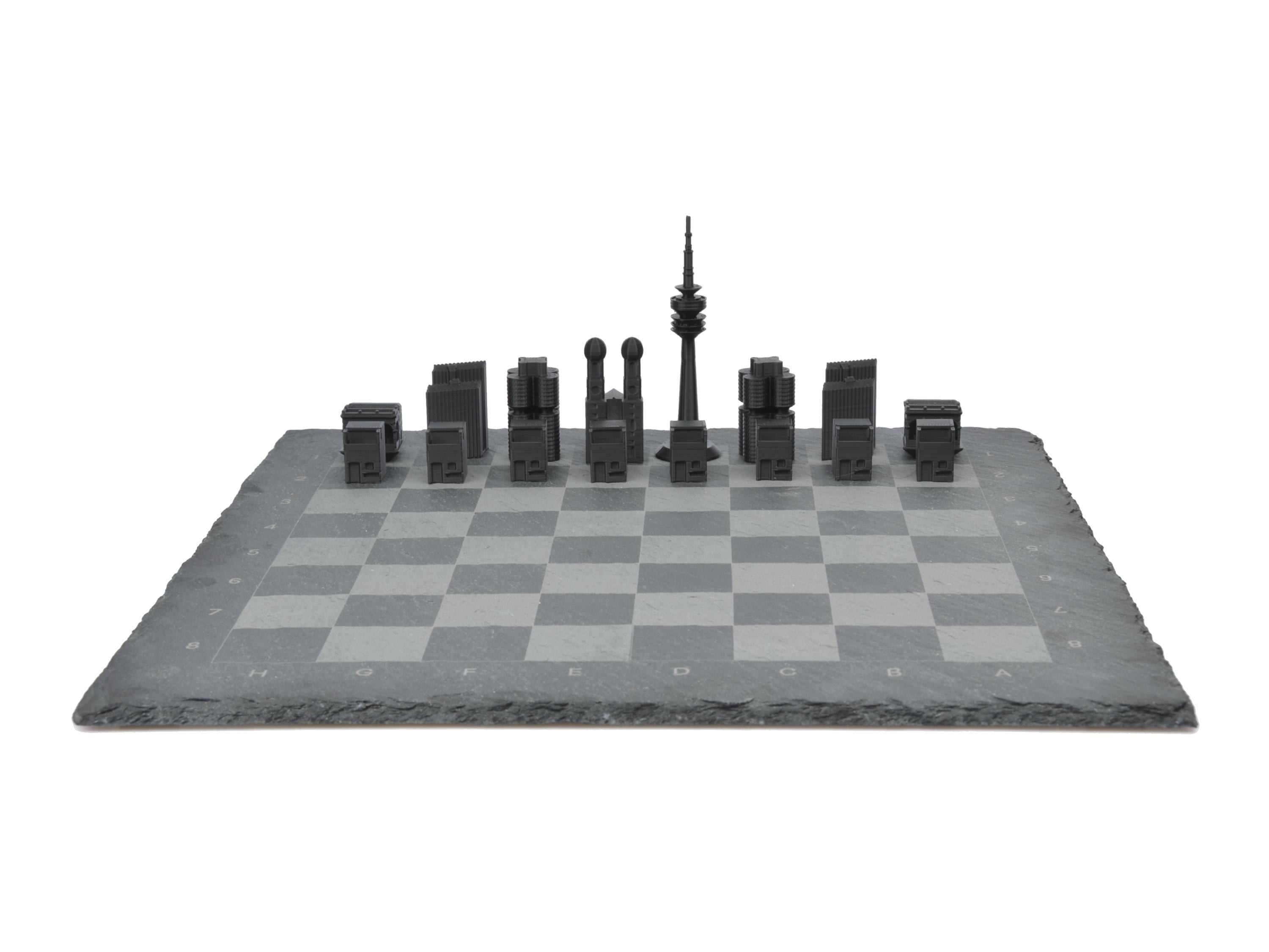 Frontalansicht München Schachspiel komplett aufgebaut: Schwarze und weiße Skyline-Figuren gegenübergestellt auf Schieferplatte.