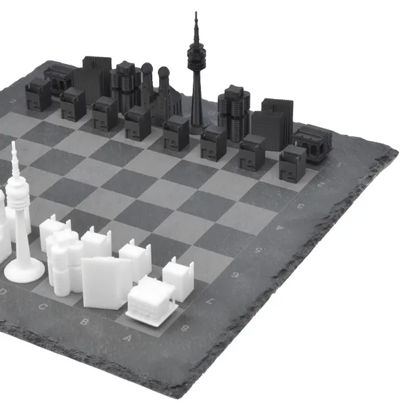 München Schachspiel Skyline Set: Edles Schieferbrett mit 3D-gedruckten Wahrzeichen wie Olympiaturm und Frauenkirche in Schwarz und Weiß.