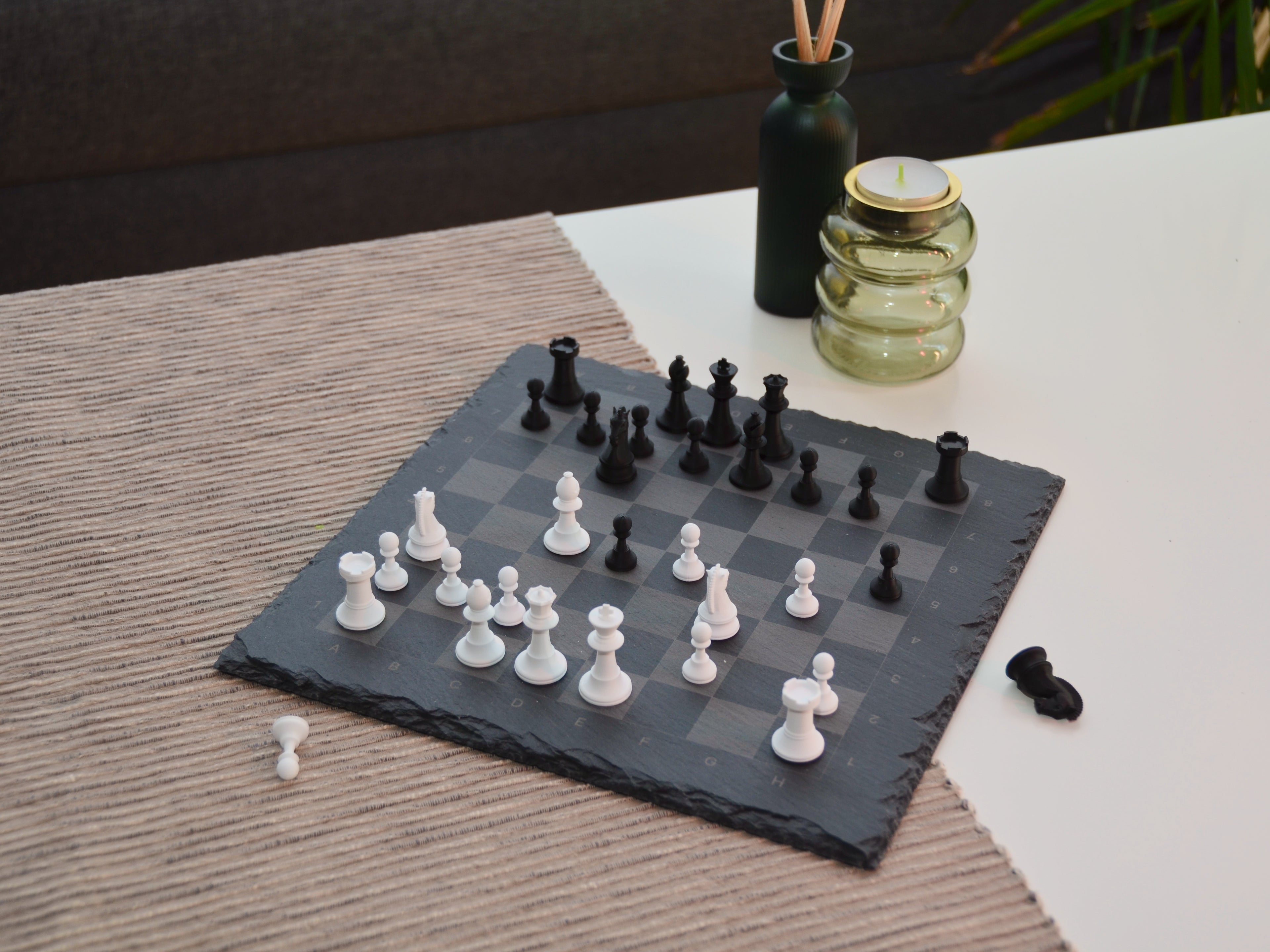 Vogelperspektive auf das aufgebaute Schachspiel: Klassisches Figurendesign trifft auf modernen grauen Schiefer.